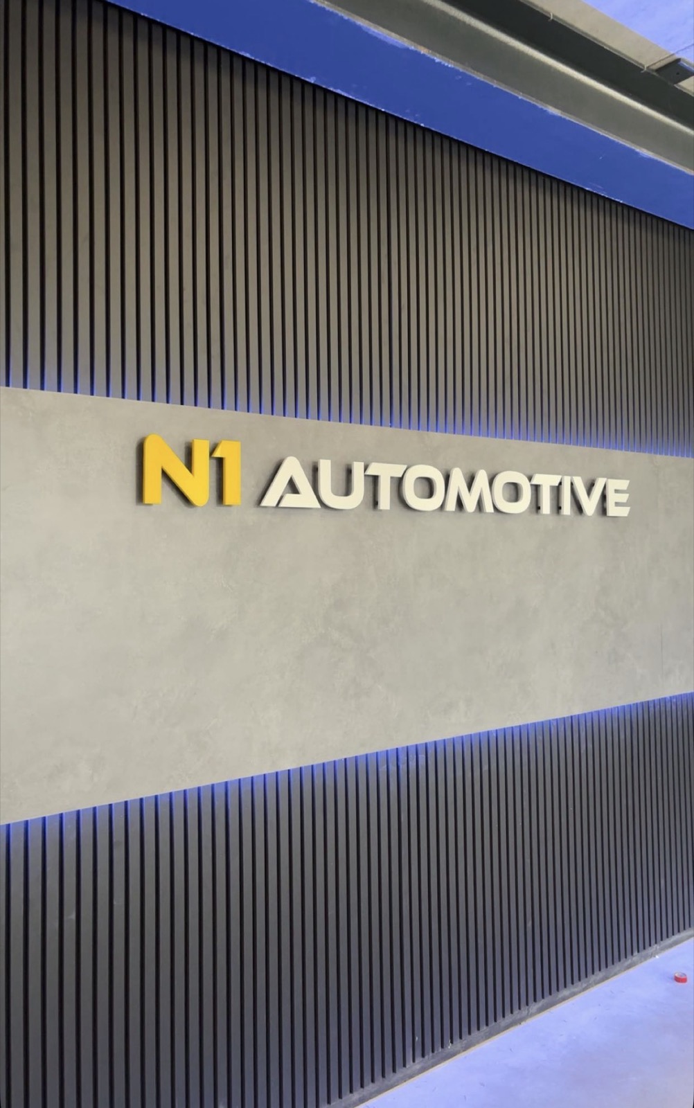 De wand in de showroom van N1 Automotive met het logo en blauwe verlichting